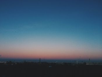 Illuminated cityscape against clear sky during sunset