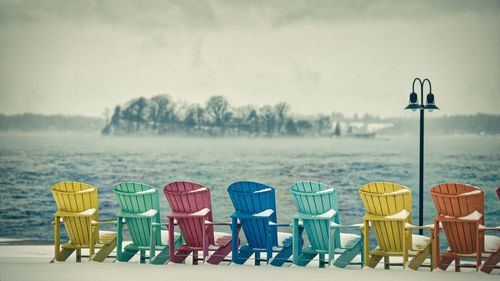 Hooded chairs on beach against sky