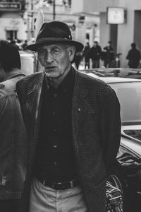 Portrait of man standing by car in city