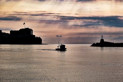Silhouette of ship in sea during sunset