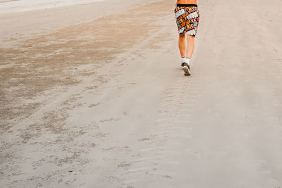 Low section of man running at beach