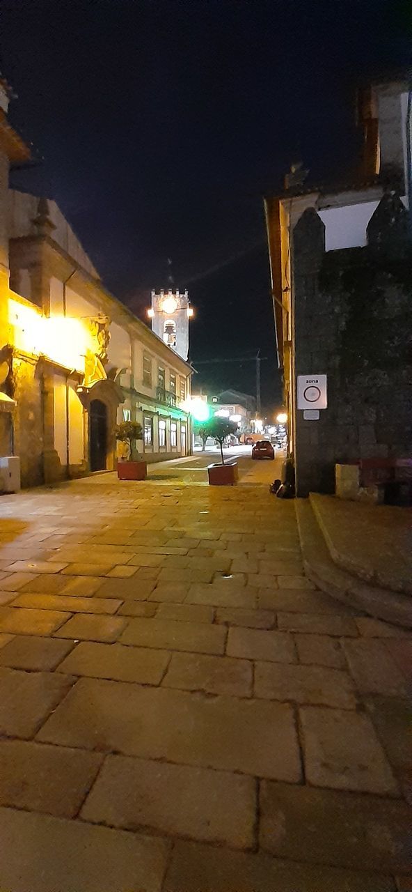 illuminated, night, architecture, building exterior, built structure, street, city, lighting equipment, direction, street light, the way forward, building, no people, transportation, footpath, road, mode of transportation, car, motor vehicle, residential district, outdoors, light, paving stone