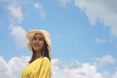 Portrait of a smiling young woman against sky