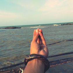 Midsection of person on sea shore against sky