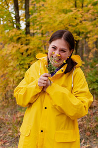 Cheerful young woman in a yellow raincoat and yellow boots poses for the camera. person