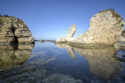 Reflection of trees in water against clear blue sky