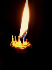 Close-up of lit candle in darkroom