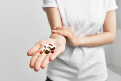 Close-up of woman holding hands over white background