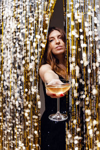 New year's eve party concept. woman holding a glass of champagne, festive shiny decor 