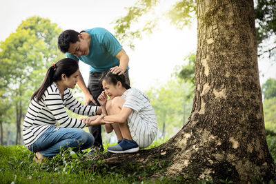 Full length of father and daughter on tree trunk