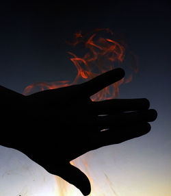 Close-up of hand against sky at night