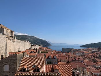 Houses by sea against clear blue sky