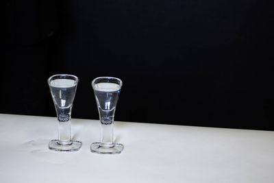 Close-up of wineglass with water on table against black background