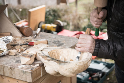 Midsection of carpenter carving wood at workshop