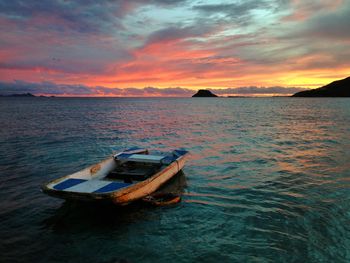 Boat moored on sea against sky during sunset