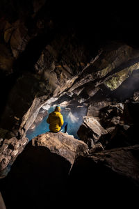 Woman sitting in front of thermal pool in cave