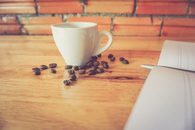 Roasted coffee beans with cup on table