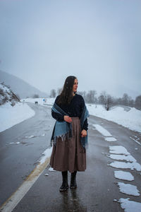 Woman standing on snow against sky during winter