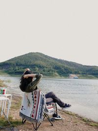 Senior man sitting on mountain against sky