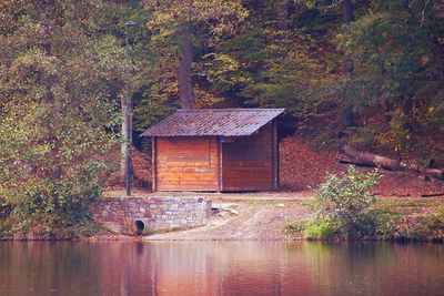 House by lake against trees in forest