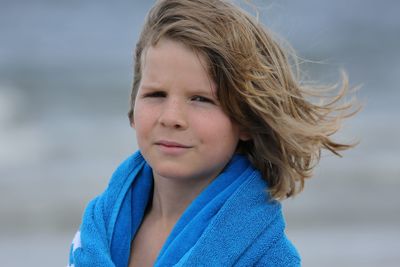 Portrait of boy with long hair wrapped in blue towel