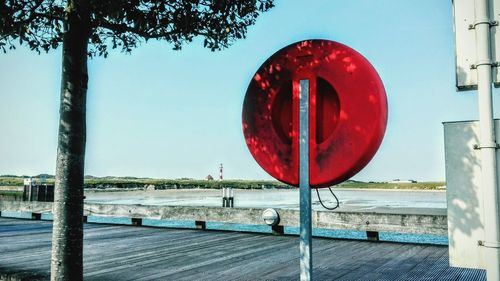 Red umbrella by sea against clear sky