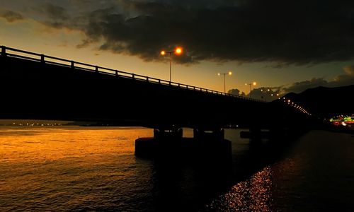 View of bridge over calm sea at sunset