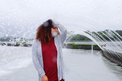 Beautiful woman standing by water against sky