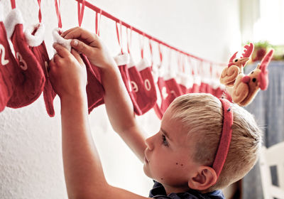 Boy with antlers retrieves gift from numbered stocking. holiday anticipation.