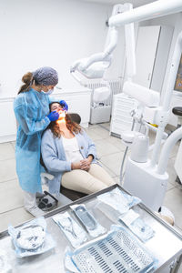 Young dentist examining patient on chair at clinic