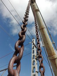 Low angle view of chains against cloudy sky