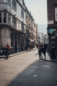 People walking on road by buildings in city