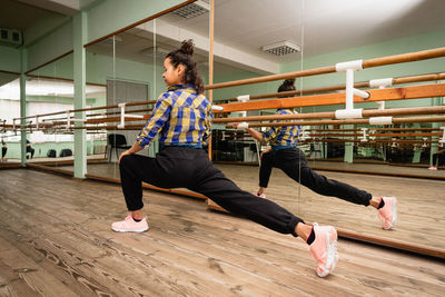 A young woman is engaged in contemporary dance alone in the choreography hall. back view