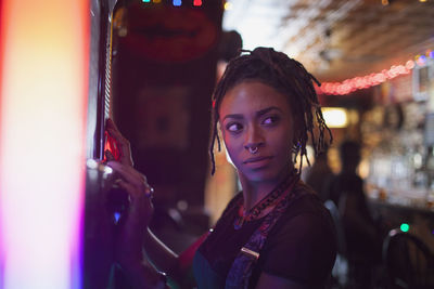 A young woman at a jukebox in a bar.