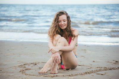Young woman sitting on shore of beach