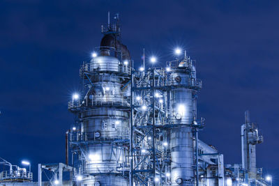 Low angle view of illuminated factory against sky at night