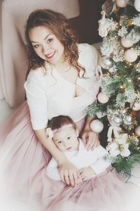 Portrait of cute baby girl sitting on bed at home