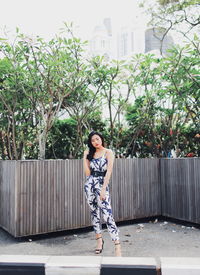 Full length of young woman standing on road against fence