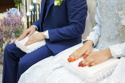 Midsection of bride and groom sitting during wedding ceremony