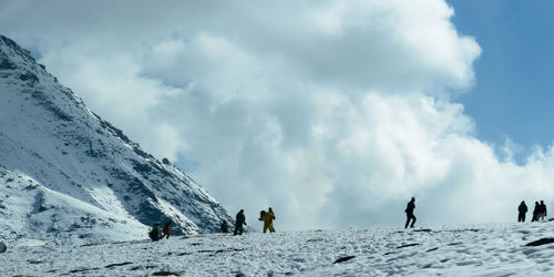 Panoramic view of people on snowcapped mountain against sky