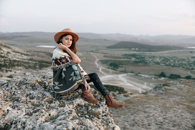 Portrait of young woman sitting on rock