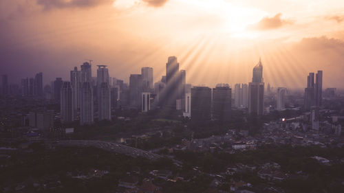 Modern buildings in city against sky during sunset