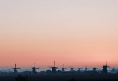 Traditional windmills against clear sky during sunset