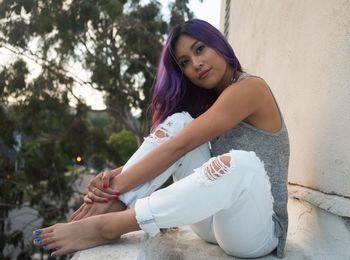 Young woman sitting on retaining wall