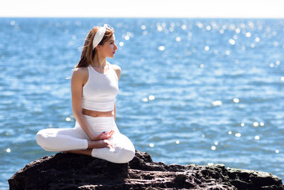 Woman doing yoga against sea