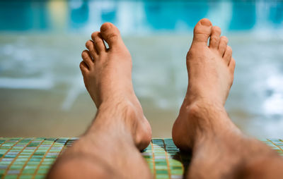 Low section of man relaxing in swimming pool