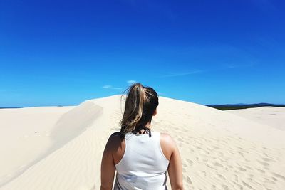 Rear view of woman standing on sand dune
