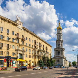 Cars on street by buildings against sky in city