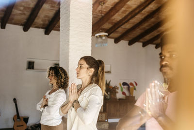 Multi racial group exercising with hands clasped in health club