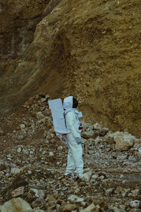 Rear view of an astronaut standing on rock